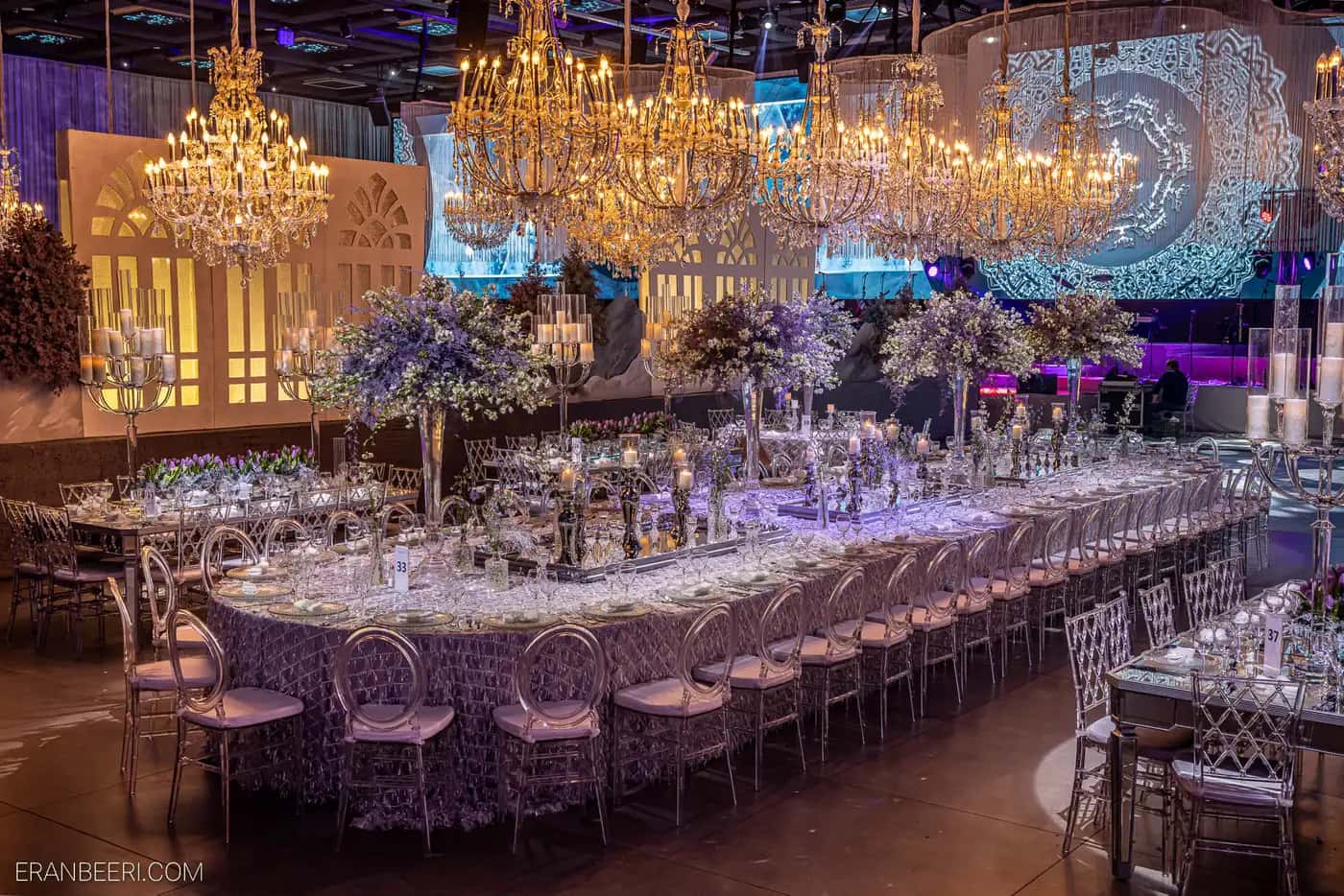 Wedding hall with crystal chandeliers, flowers and purple table settings